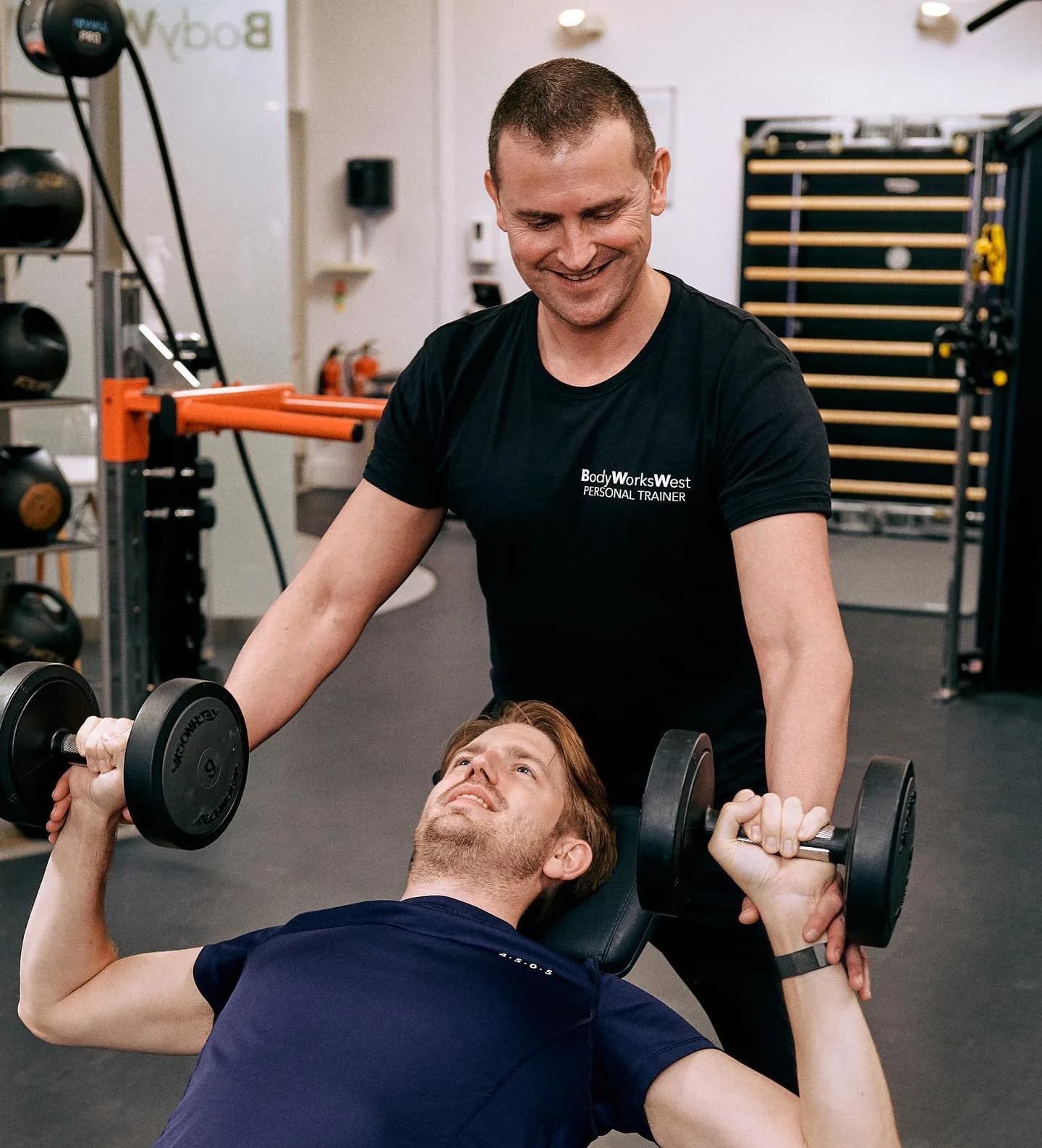 Personal trainer spotting a member during a bench press at Body Works West