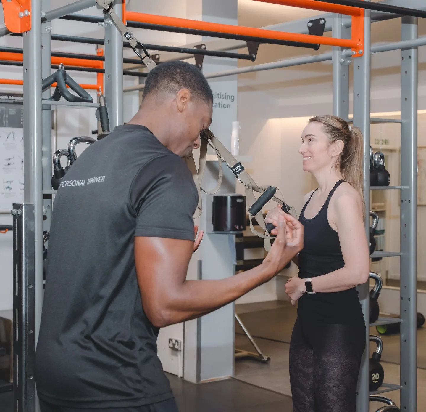 Personal trainer guiding a member through a TRX exercise at Body Works West